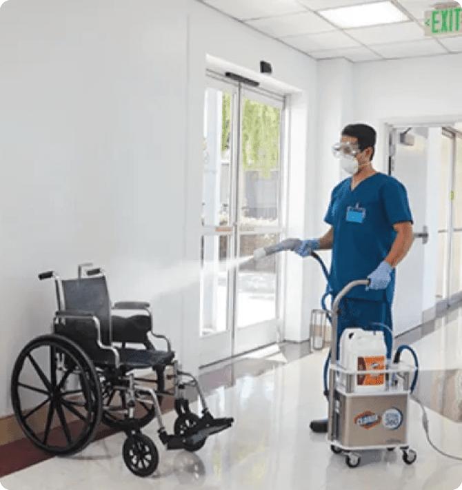 Staff member cleaning a wheelchair in a hallway