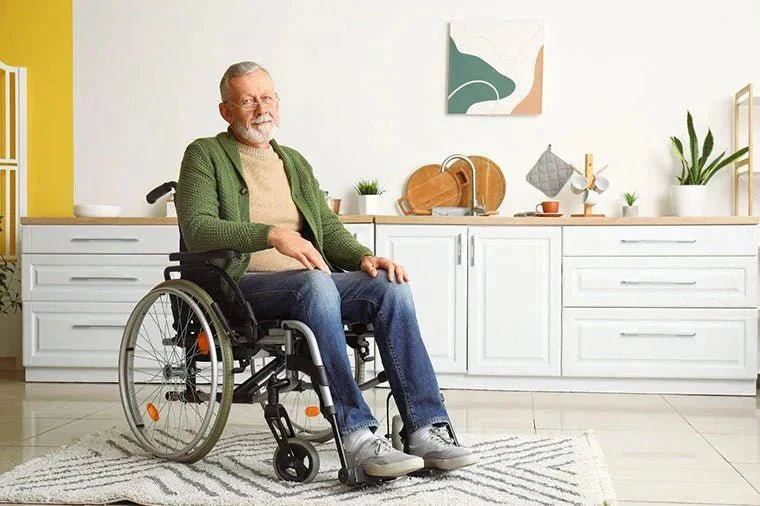Older man sitting in a wheelchair at home